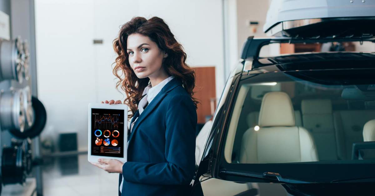 Women hold an ipad next to a car